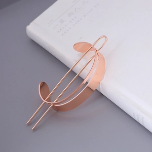 Detail of rose gold minimalist hair pin featuring curved metal plate and double parallel prongs