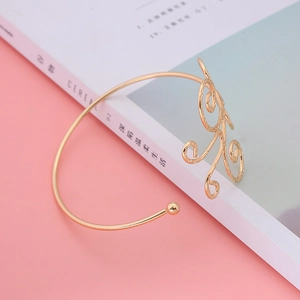 Detailed macro view of a golden open arm cuff bracelet with elegant hollow spiral patterns