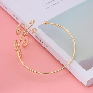 Golden bohemian open cuff bracelet with intricate swirl design on a soft pink background