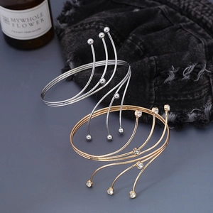 Dettaglio di bracciali rigidi multistrato in oro e argento con strass e perline