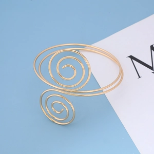 Dettaglio del bracciale da braccio a spirale dorata con metallo strutturato e apertura regolabile