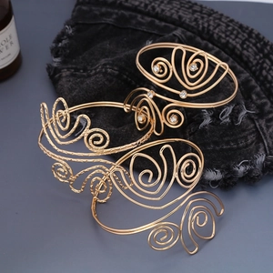 Dettaglio di bracciali a spirale dorati con strass su sfondo di denim scuro