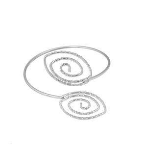 Macro detail of silver bohemian spiral metal arm cuff with delicate geometric swirl texture
