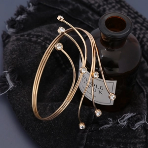 Dettaglio di un bracciale dorato multistrato con strass su sfondo denim nero