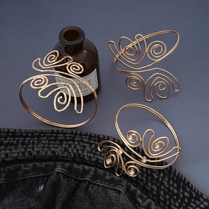 Dettaglio dei bracciali da braccio in oro con texture a spirale e strass lucidi