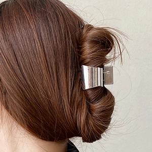Minimalist silver metal hair claw clip for women in a sleek polished finish on dark hair