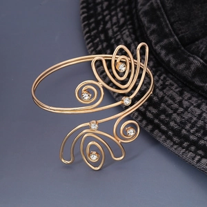 Dettaglio di un bracciale a spirale dorato con decorazioni in cristallo lucente