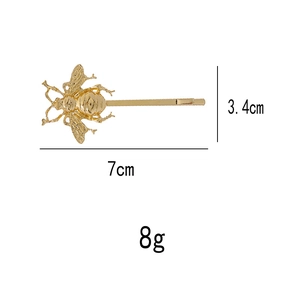 Detailed view of the golden metal bee hair clip with dimensions 7cm by 3.4cm
