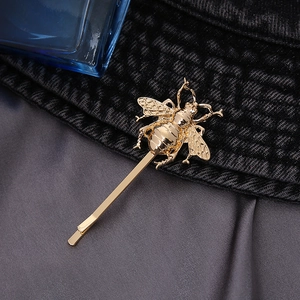 Detailed close-up of a vintage golden bee hair pin with intricate wings and polished finish
