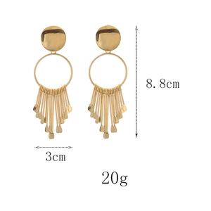 Gros plan de boucles d'oreilles dorées à pompons avec dimensions de 8,8 cm sur 3 cm