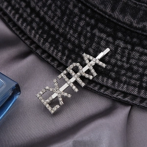 Sparkling silver EXTRA letter hair clip with inlaid rhinestones on a stylish fabric background