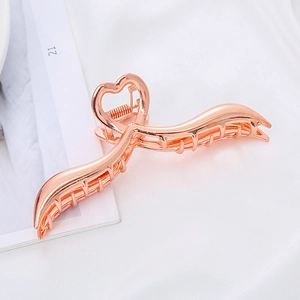 Dettaglio molletta per capelli in metallo oro rosa con design a onda e cuore