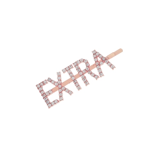 Macro shot of rose gold metal hair clip with sparkling rhinestones spelling EXTRA