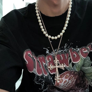 Detail showing layered gold cross necklace with pearls on male model wearing black tee