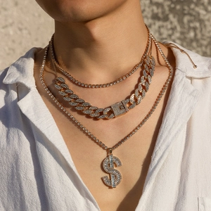 Close-up of gold layered Cuban link necklace with iced out dollar sign pendant on model