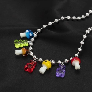 Détail de breloques ours et champignons colorés sur un collier de perles argentées