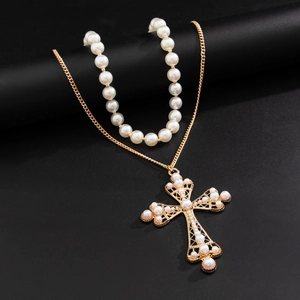 Detail of a layered hip-hop necklace featuring a gold cross pendant with inset pearls