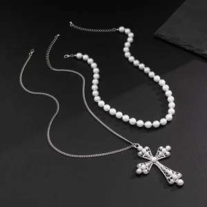 Detail of layered hip-hop necklaces featuring a cross pendant and pearl strand on stone