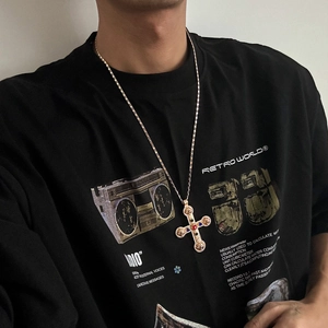 Detail of hip hop gold necklace featuring a large vintage cross pendant with colored gems