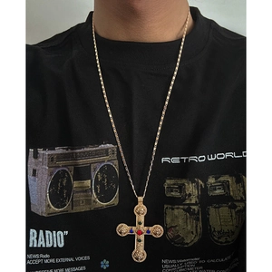 Close-up of gold cross pendant with red and blue beads on a vintage hip-hop necklace
