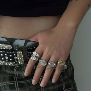 Nahaufnahme von Hip-Hop-Silberringen mit gelbem Edelstein und flüssiger Metalltextur