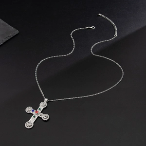 Close-up of silver cross necklace with red gemstone and adjustable O-link chain