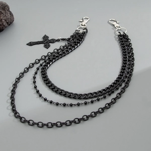 Détail d'une chaîne de pantalon punk noire à trois couches avec pendentif croix et fermoirs
