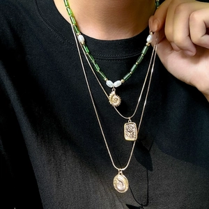 Détail du collier multi-rangs avec pendentif coquillage, perles vertes et médaillon