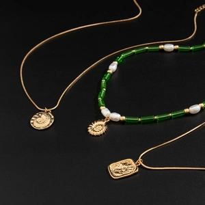 Gros plan de pendentifs en relief de coquillage sur chaînes dorées et perles