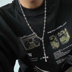 Detail of silver cross necklace with colorful gemstones on a street style model