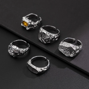 Detailansicht von fünf silbernen Ringen mit Textur und einem gelben Edelstein als Akzent