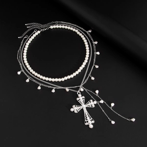 Détail du collier de perles multicouches avec pendentif croix évidée ornée