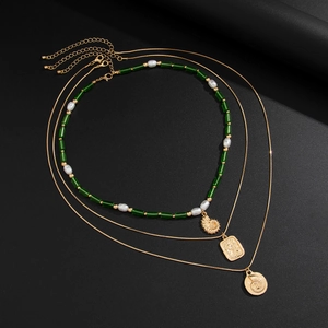 Ensemble de colliers superposés dorés avec pendentif conque, perles vertes et nacres
