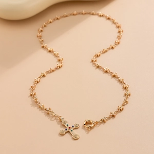 Detailed close-up of a vintage gold cross pendant featuring colorful gemstone accents