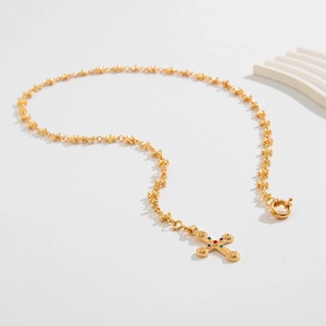 Close-up of gold star chain and vintage cross pendant with colorful gemstones