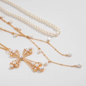 Détail du pendentif croix hip-hop avec perles sur une chaîne de perles dorée