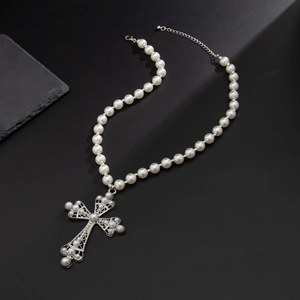 Détail du collier croix avec perles blanches et fermoir mousqueton argenté sur pierre noire