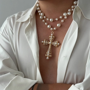 Close-up of double layer pearl necklace with a large gold hollow cross pendant