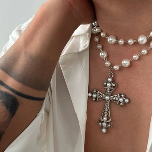 Detail of double-layer pearl necklace with a vintage gothic cross pendant on a model