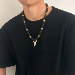 Detail of shark tooth pendant on a rasta-colored beaded necklace for men