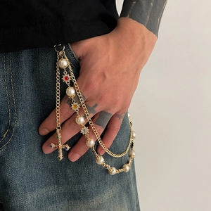 Detail of multilayer punk waist chain with faux pearls, star motifs and a cross pendant