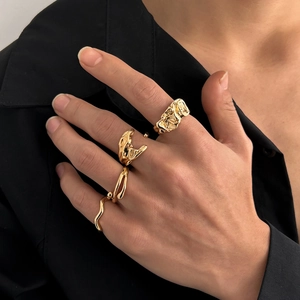 Detailaufnahme goldener Lava-Ringe mit unregelmäßigen organischen Mustern auf den Fingern