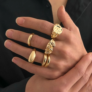 Detail view of 4-piece gold rings with irregular liquid metal texture and smooth bands