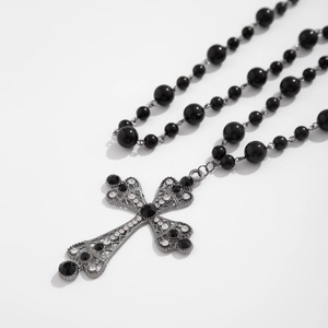 Macro detail of gothic cross pendant with black beads and sparkling rhinestones