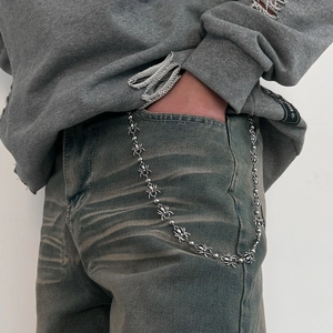 Detail of a punk style silver spider waist chain clipped on denim jeans for a hip hop look