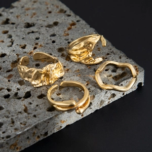 Makro-Detail von goldfarbenen Ringen mit Lava-Textur auf grauem Stein mit Metallic-Finish