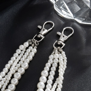 Detail view of layered pearl chains for jeans with silver lobster clasp on black velvet