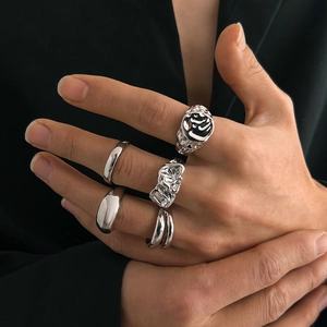 Close-up of five silver liquid metal rings with irregular folds and abstract smiley face