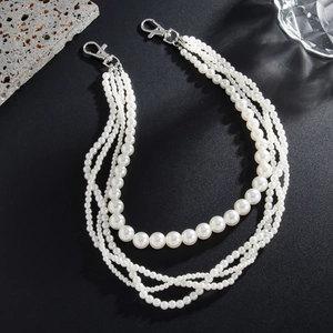 Detail of four-layer white pearl chain accessory with silver lobster clasps for pants
