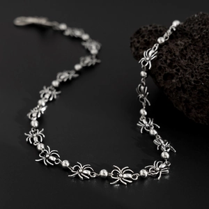 Detail of silver spider link metal chain with punk gothic aesthetic on volcanic rock
